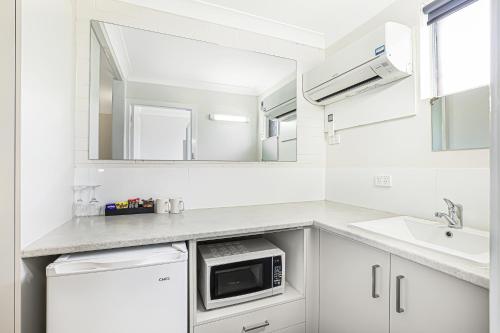 Acacia Motor Inn في بوندابرج: مطبخ أبيض مع حوض وميكروويف