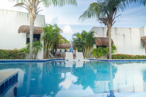 a swimming pool at a resort with palm trees at Oasis Tajaja Pousada Boutique na Costa do Conde in Jacumã