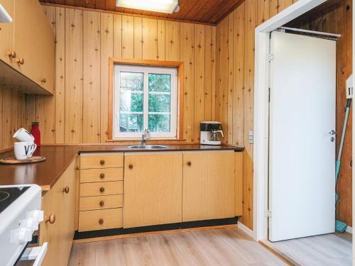 a kitchen with wooden walls and a sink and a window at 4 person holiday home in Ansager in Ansager