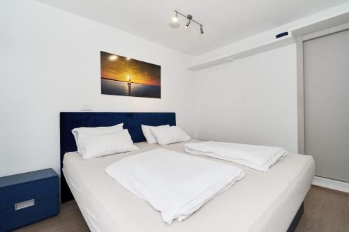 een slaapkamer met een bed met witte lakens en een schilderij aan de muur bij Matic Murgle Atrium Apartment in Ljubljana