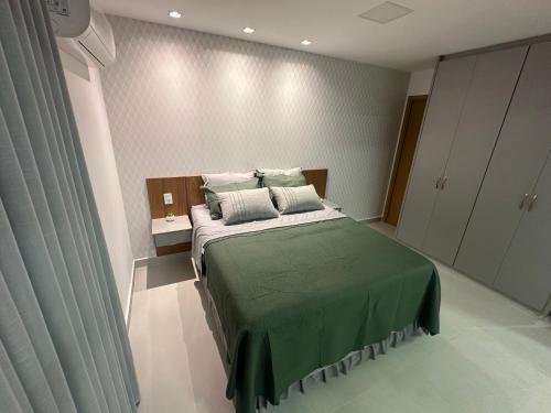 a bedroom with a bed with green sheets and pillows at Studio Premium com lazer completo , ótima localização in Goiânia
