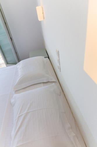 a bedroom with a bed with white sheets and a window at Roses Beach in Parikia