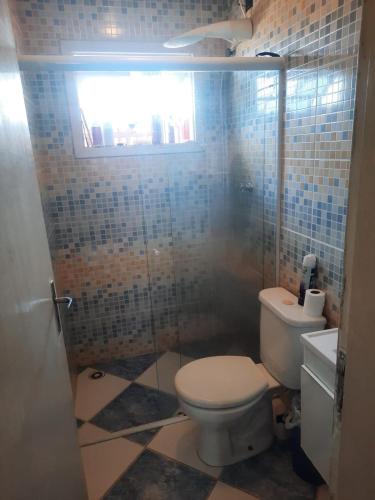a bathroom with a toilet and a glass shower at Flat I - 50 Metros da Praia in Caraguatatuba