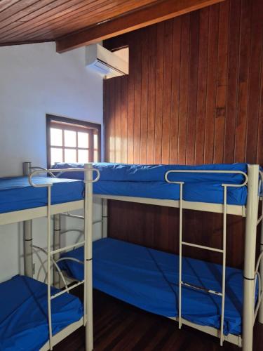 two bunk beds in a room with a wooden wall at Flat I - 50 Metros da Praia in Caraguatatuba