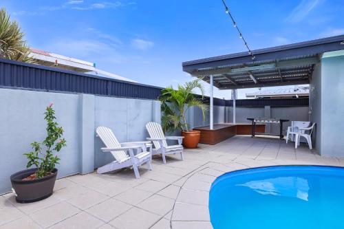 a patio with chairs and a table and a pool at Acacia Motor Inn in Bundaberg