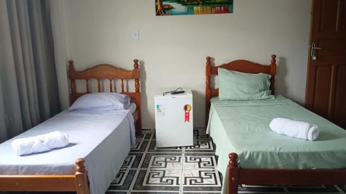 een kamer met twee bedden en een koelkast op de vloer bij Pousada Rose Alves in Cachoeiras de Macacu