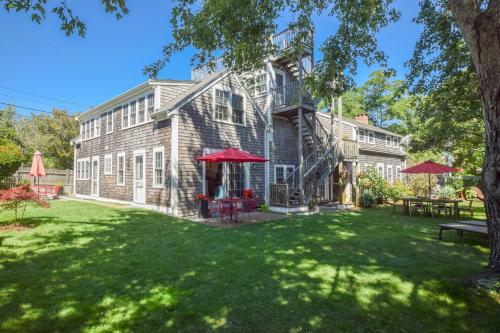 普罗温斯敦East End Condo w Beach Access的一栋老式砖房，院子里摆放着桌椅。