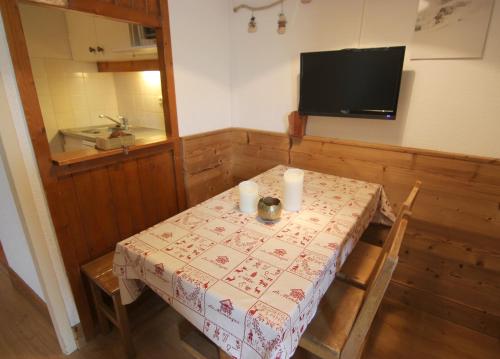 a room with a table with two candles and a television at Zenith Appartements VTI in Val Thorens