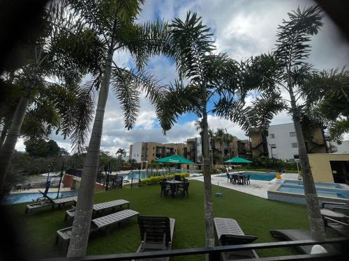 een zwembad met palmbomen en tafels en stoelen bij Modern apartment surrounded by nature in La Tebaida