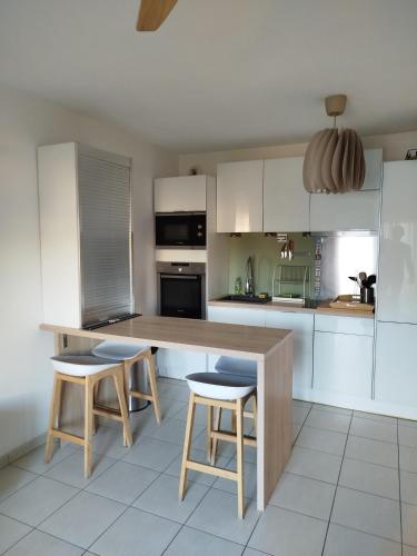 eine Küche mit einem Holztisch und zwei Hockern in der Unterkunft Le Vallon in Marseille