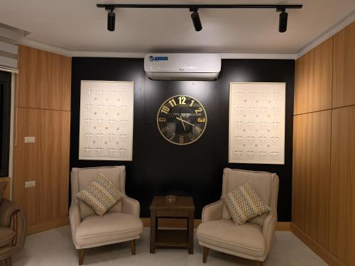 um quarto com duas cadeiras e um relógio na parede em الكوت للأجنحة السكنية - Alkout Suites em Irbid
