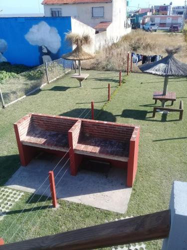 a park with benches and umbrellas on the grass at Departamento santa elena in Frente Mar
