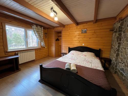 ein Schlafzimmer mit einem Bett in einem Holzzimmer in der Unterkunft Karpatske Vidlunnya in Mykulytschyn