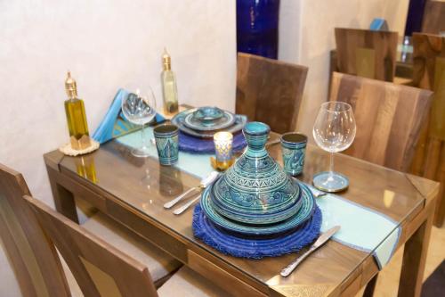 un tavolo con un piatto blu e bianco e bicchieri da vino di Riad La Rose Orientale Marrakech a Marrakech