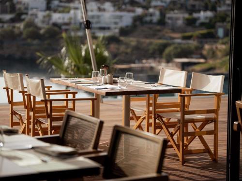 a wooden table and chairs on a deck with a view at The Bodrum Hotel Yalıkavak - MGallery Collection in Yalıkavak