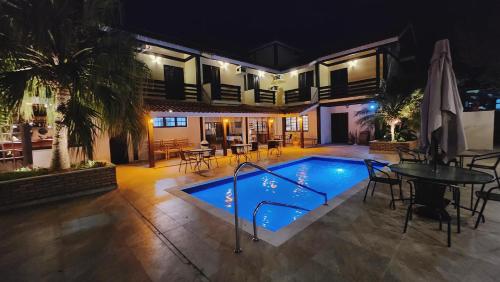 uma casa com piscina à noite em Pousada Vitória Régia - Hotel Costeira em São Sebastião
