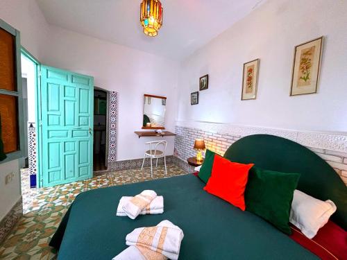 a bedroom with a green bed with colorful pillows at Riad Nostalgie of Tetouan in Tétouan