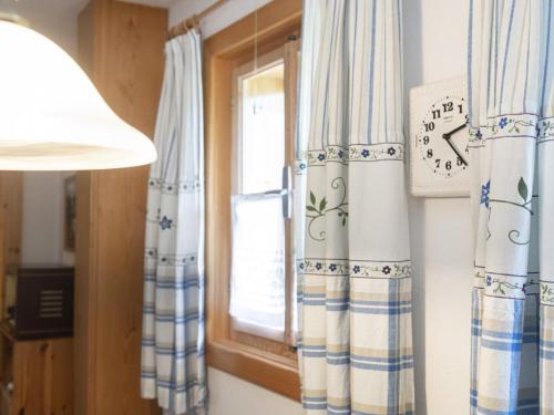 Una ventana con cortinas azules y blancas y un reloj. en Sixhäusl, en Kirchberg in Tirol