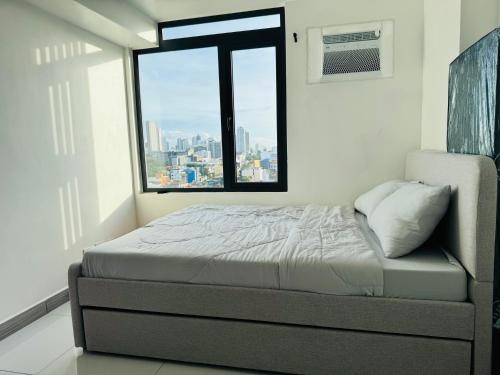 una cama en una habitación con una ventana grande en ARC Towers Condominium, en Cebú