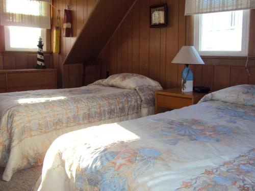 Ocean Side Home In Brant Beach 36525 في Brant Beach: غرفة نوم بسريرين ومصباح ونوافذ