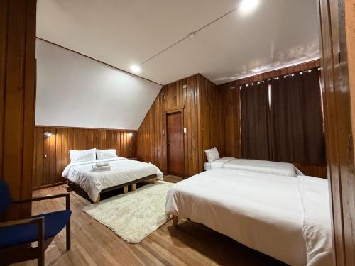 Dos camas en una habitación con paredes de madera. en Travels Hotel, en Osorno