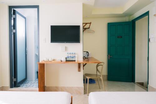 Una habitación con un escritorio y un televisor y una puerta. en De Rivé Homestay 3 - Bến Ninh Kiều, en Can Tho