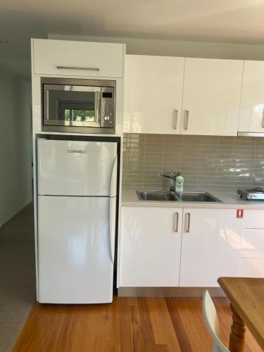 a white kitchen with a refrigerator and a microwave at 20 Bradley in Coles Bay