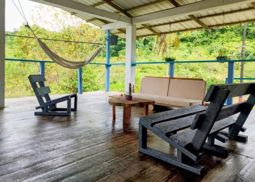 Lunaria Pacífico في El Valle: شرفة مع كرسيين وطاولة وأرجوحة