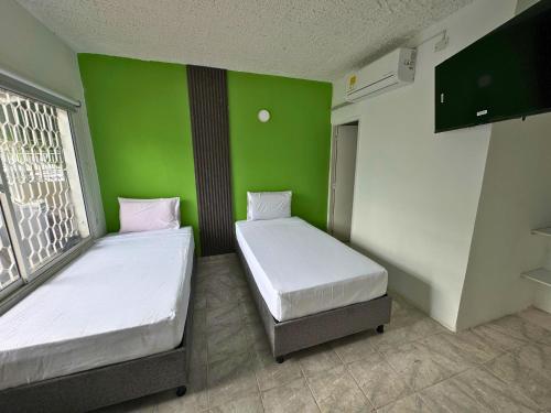 twee bedden in een kamer met een groene muur bij Hotel Casa Manzanares in Santa Marta