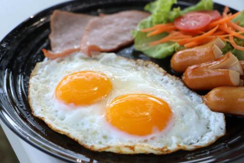 Deux œufs et du bacon dans une assiette avec des légumes dans l'établissement บ้านครูเอ๋โฮมสเตย์ Baankruae Homestay, 