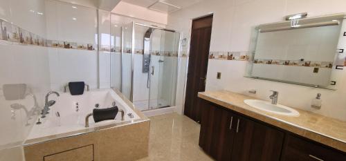 een badkamer met een bad, een wastafel en een douche bij Chalet Tunari in Quillacollo