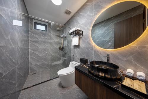 a bathroom with a sink and a toilet and a mirror at Cat Ba Wistaria Hotel- Jacuzzi Rooftop & Fitness in Cat Ba