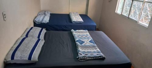 two beds in a room with blue sheets and pillows at Casa familiar ampla in São Gabriel