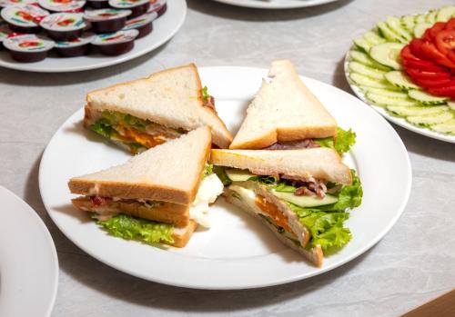 a white plate with a sandwich and a salad at Cat Ba Wistaria Hotel- Jacuzzi Rooftop & Fitness in Cat Ba