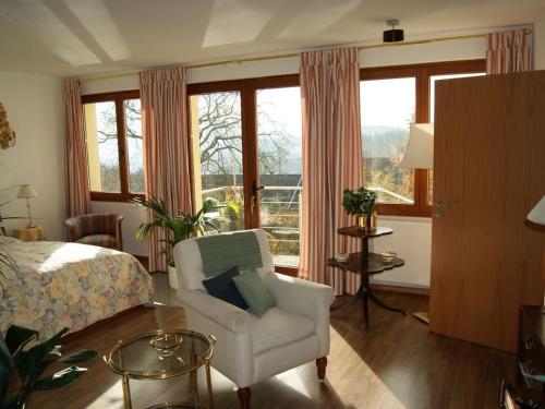 een slaapkamer met een bed, een stoel en ramen bij Pension Espenhof in Strüth