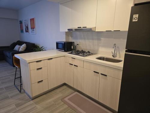 eine kleine Küche mit Spüle und Mikrowelle in der Unterkunft Departamento premium en el corazón de la ciudad in Mexicali