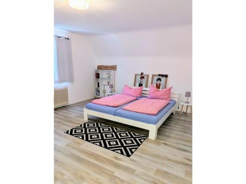Un dormitorio con una cama con almohadas rosas y una alfombra. en Holiday home with 1 bedroom, en Friesenheim