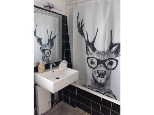 Un baño con lavabo y cortina de ducha con cabeza de ciervo. en Holiday home with 1 bedroom, en Friesenheim