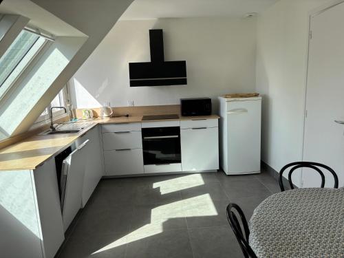 een keuken met witte kasten en een witte koelkast bij Le premier etage indépendant dans une maison avec grand parc in Lorient