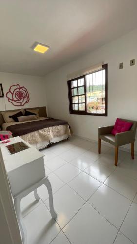 ein Schlafzimmer mit einem Bett, einem Tisch und einem Stuhl in der Unterkunft Casa de Praia - 4 quartos Centro in Bombinhas