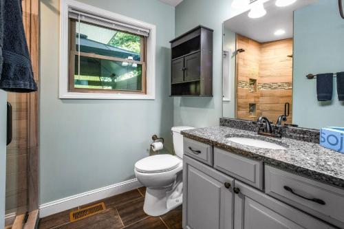 a bathroom with a toilet and a sink and a window at Distiller's Den in Gatlinburg