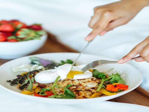 uma pessoa a comer uma salada com um garfo e uma faca em Novotel Nairobi Westlands em Nairobi