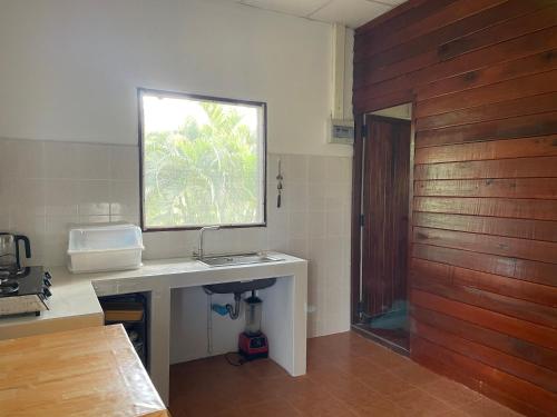 a bathroom with a sink and a window and a wooden door at Nazo Boutique Bungalows in Wok Tum