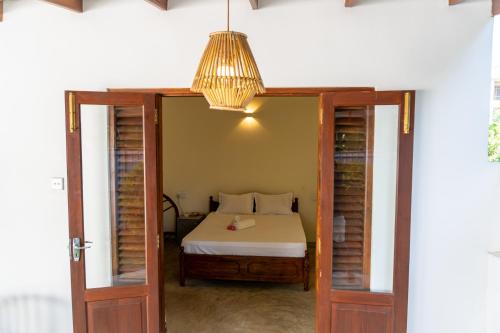 een slaapkamer met een bed en een hanglamp bij Margosa Ahangama in Ahangama
