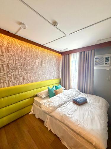 a bedroom with a bed with a yellow wall at House of Keul - 2BR cozy condo in Dumaguete with pool and free laundry for long term guests up to 4 pax in Piapi
