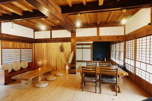 a dining room with a wooden table and chairs at 農ある暮らしの宿 古民家 天地 in Minamiizu