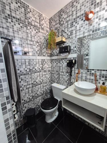 a bathroom with a white toilet and a sink at Studio completo e aconchegante com vaga de garagem in Campinas