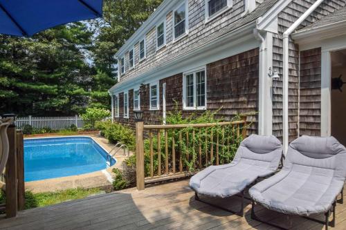 een patio met 2 stoelen en een zwembad bij Pool Half Mile to Beach in Harwich