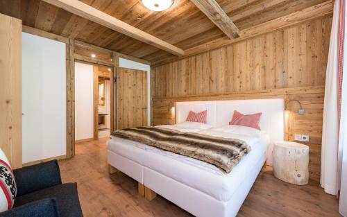 a bedroom with a white bed and wooden walls at Aurina Lodges in Lutago