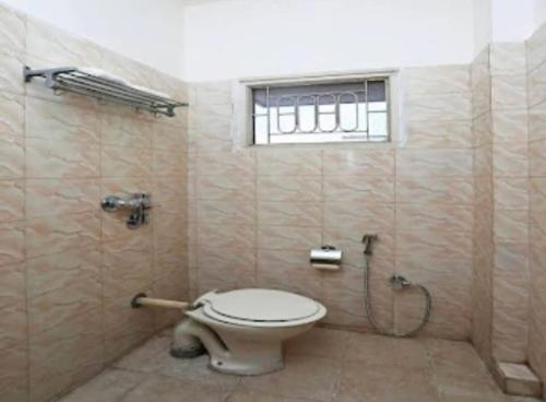 a bathroom with a toilet and a shower with a window at Hotel Vijay Palace in Bhopal